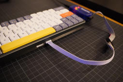 the fully assembled keyboard on a cutting mat, a ribbon cable running out of the side of its base to the SinoLink