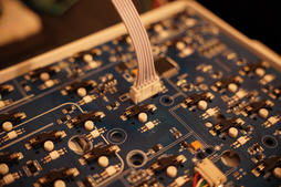 a ribbon cable plugged into a white connector on the Air60's blue PCB, between the switch sockets
