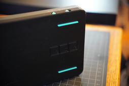the base standing on edge, showing the teal rubber strips and the three square debug access ports in its side