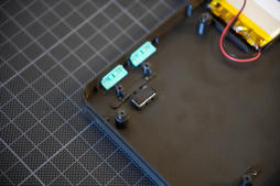 close-up inside a corner of the base: printed standoffs, the two teal mode switches and the edge of the battery