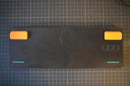 the underside of the printed base, showing the curved seam between the two printed halves, the two orange flip-out feet and the teal rubber strips
