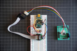 the same Nano on the breadboard, wired by jumper wires to a bare Sinowealth chip on a green breakout board